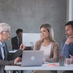 Serious senior agent talking to a couple during a meeting in the office