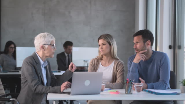 Serious senior agent talking to a couple during a meeting in the office