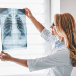 Caucasian adult female doctor looking at x-ray